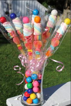 a vase filled with candy and candies on top of a white table outside in the grass