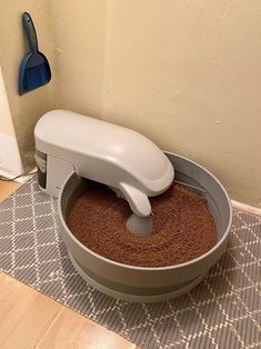 a cat litter box on the floor with a brush in it