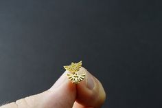 a person holding a tiny gold ring with a sun design on the front and side