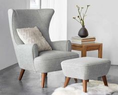 a chair and ottoman in a living room with a vase on the table next to it