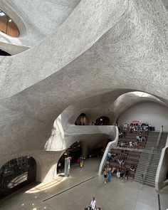 the interior of a building with stairs and people sitting on benches in front of it