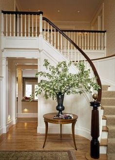 there is a vase with flowers on the table in front of the stair case that leads up to the second floor