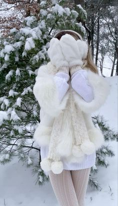 a woman is standing in the snow with her arms wrapped around her head and wearing a white coat