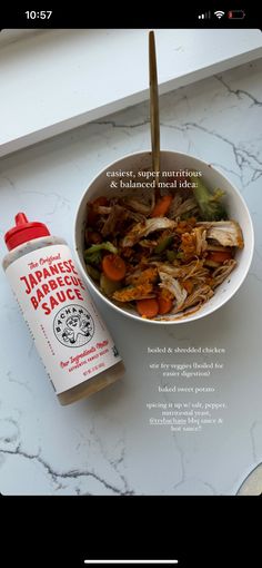 a white bowl filled with food next to a bottle of sauce on top of a counter