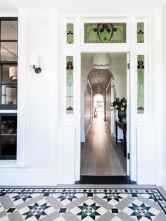 an open door leading to a hallway with stained glass panels on the walls and floor