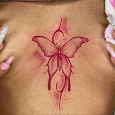 a woman's back with a butterfly tattoo on it and pink nail polishes