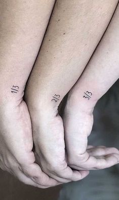 two people holding hands with numbers on their wrists and one has a small tattoo on the wrist