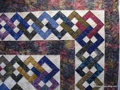 a quilted wall hanging on the side of a building with different colored blocks in it