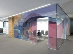 an office with glass partitions and chairs in the middle of it, all painted multicolored