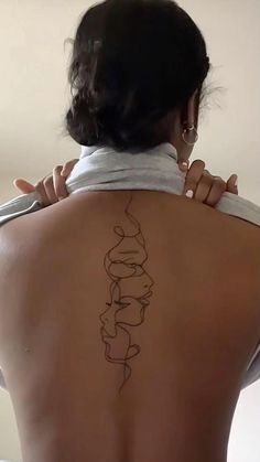 a woman with a tattoo on her back holding a pair of scissors to her neck