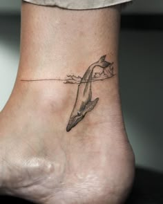 a small tattoo on the ankle of a woman's foot, depicting a dolphin