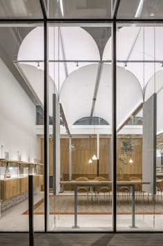 the inside of a building with glass walls and wooden tables in it's center