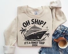 a sweater with the words oh ship it's a family trip on it next to a cup of coffee