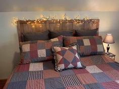 a bed with plaid comforter and pillows in a room decorated with christmas lights on the headboard