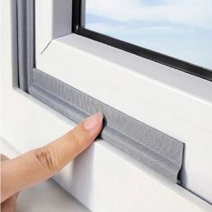 a hand is pointing at the window seal