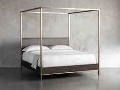 a white bed with a metal frame and headboard is shown in front of a concrete wall