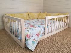 a white crib with yellow and blue pillows on it's sides, next to a bed