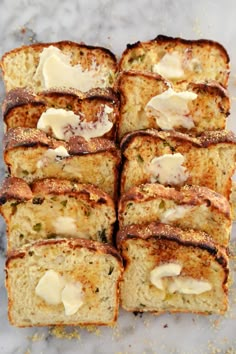 slices of bread with butter and herbs on them sitting on a marble counter top, ready to be eaten