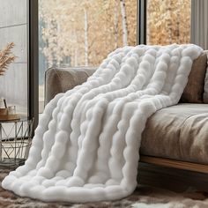 a large white blanket sitting on top of a couch in front of a windowsill