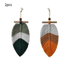 two different colored leaves hanging from a wooden hanger on a white background, one is green and the other is orange