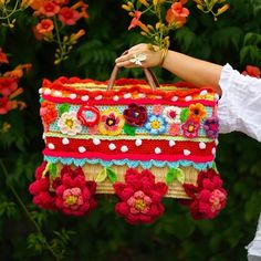 a woman is holding a crocheted purse with flowers on it