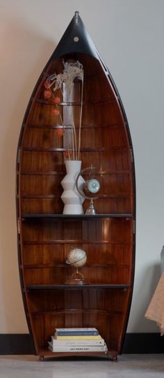 a wooden shelf with vases and other items on it next to a wall mounted lamp