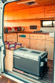 the inside of a van with an open door and storage compartment on the side, filled with items