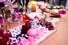 the table is covered with pink and white candies, chocolates, and wine glasses