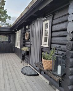 a wooden house with black siding and wood flooring on the front porch, next to a potted plant