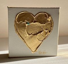 a white and gold card with a heart cut out of it's side on a table