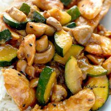 chicken and zucchini stir - fry with rice on a white plate, ready to be eaten