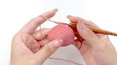 two hands holding yarn and knitting needles over a ball of yarn with the needle hooked up to it