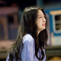 a woman with long hair standing in front of a train