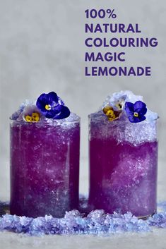 two glasses filled with purple liquid and topped with blue pansies, surrounded by snow