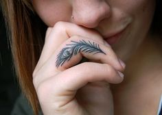 a woman with a feather tattoo on her finger