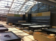 tables and benches are lined up against the wall in an empty room with large windows