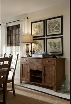 a dining room table and chairs with pictures on the wall above it in front of a window