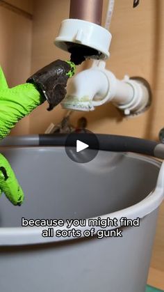 a green stuffed animal sitting in a bucket next to a faucet