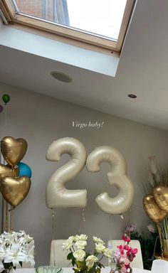 balloons and flowers are on the table in front of the number twenty - three sign