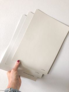 a person is holding three sheets of white paper