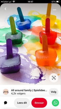 four popsicles with different colors on them sitting in the middle of a table covered in melted paint