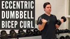 a man holding two dumbs in front of a sign that says eccentric dumbbell bice curl