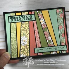 a hand holding up a thank card with flowers and stripes on it's side