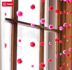 pink and red pom - poms hanging from the window