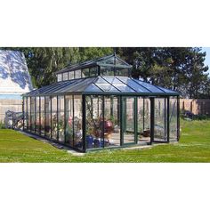 a green house sitting on top of a lush green field