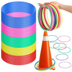 a stack of colorful plastic rings next to a cone and orange cone with one hand