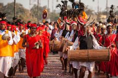 a group of people in red and yellow outfits carrying large wooden baskets on their heads