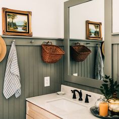 a bathroom with green walls and white counter tops, two pictures hanging on the wall