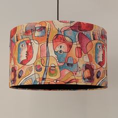 a multicolored lamp shade hanging from a ceiling fixture with an abstract painting on it