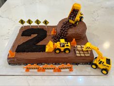 a birthday cake with construction trucks and dirt on the top is for two year old